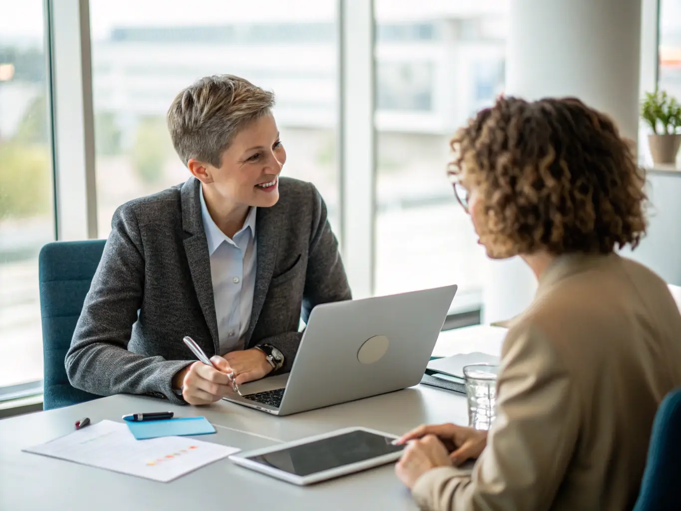 A consultant working with a client on a laptop, demonstrating AI software for business automation, in a modern office setting.
